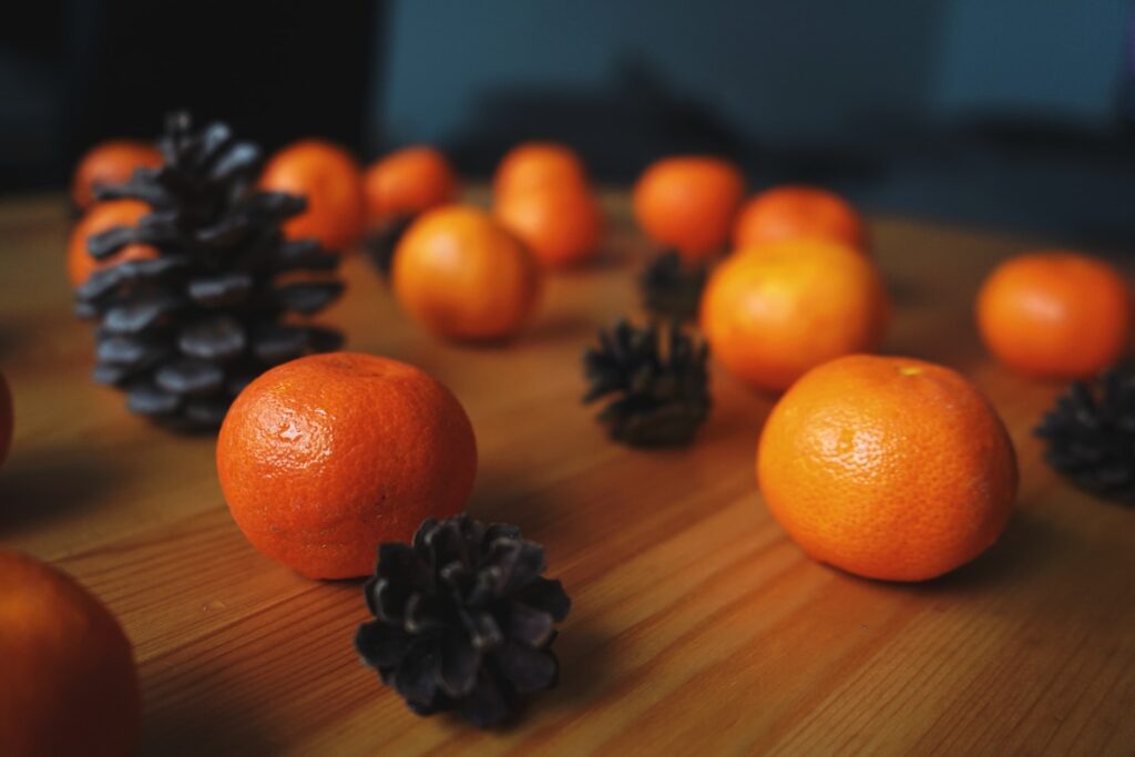a wooden table topped with oranges and pine cones